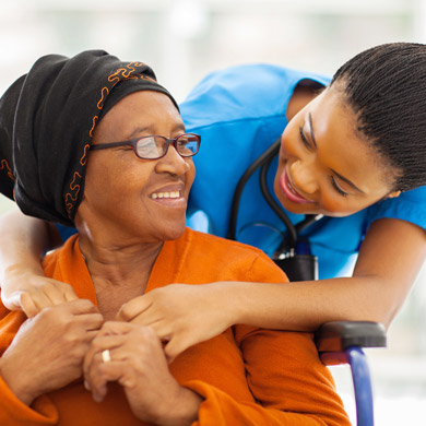 Young smiling female caregiver assisting smiling female senior